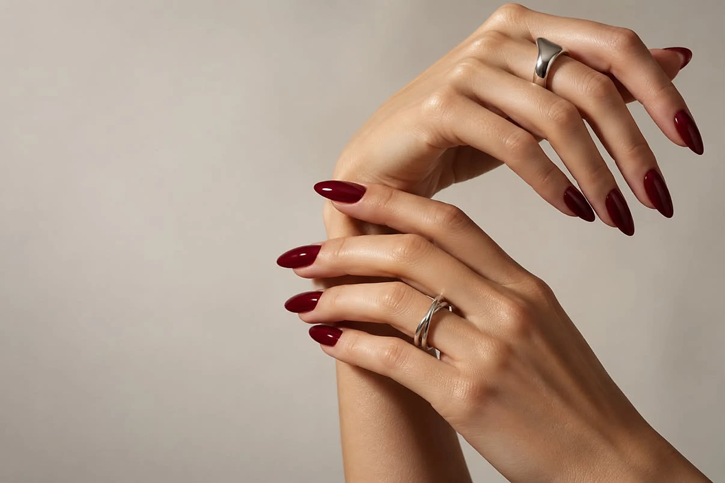 Mains aux ongles bordeaux, bagues en argent